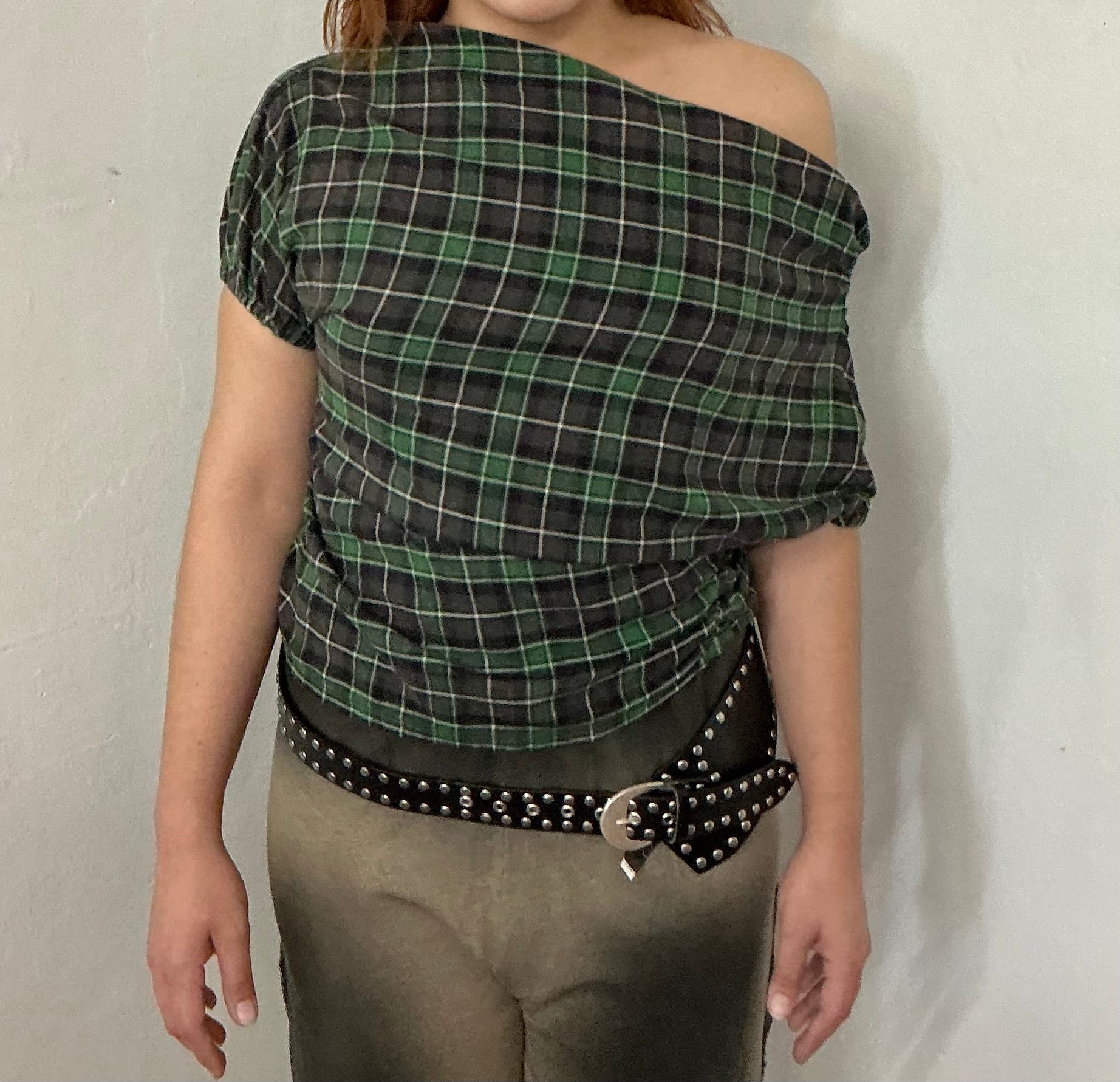 Person wearing a green and black plaid top with a grunge vibe 